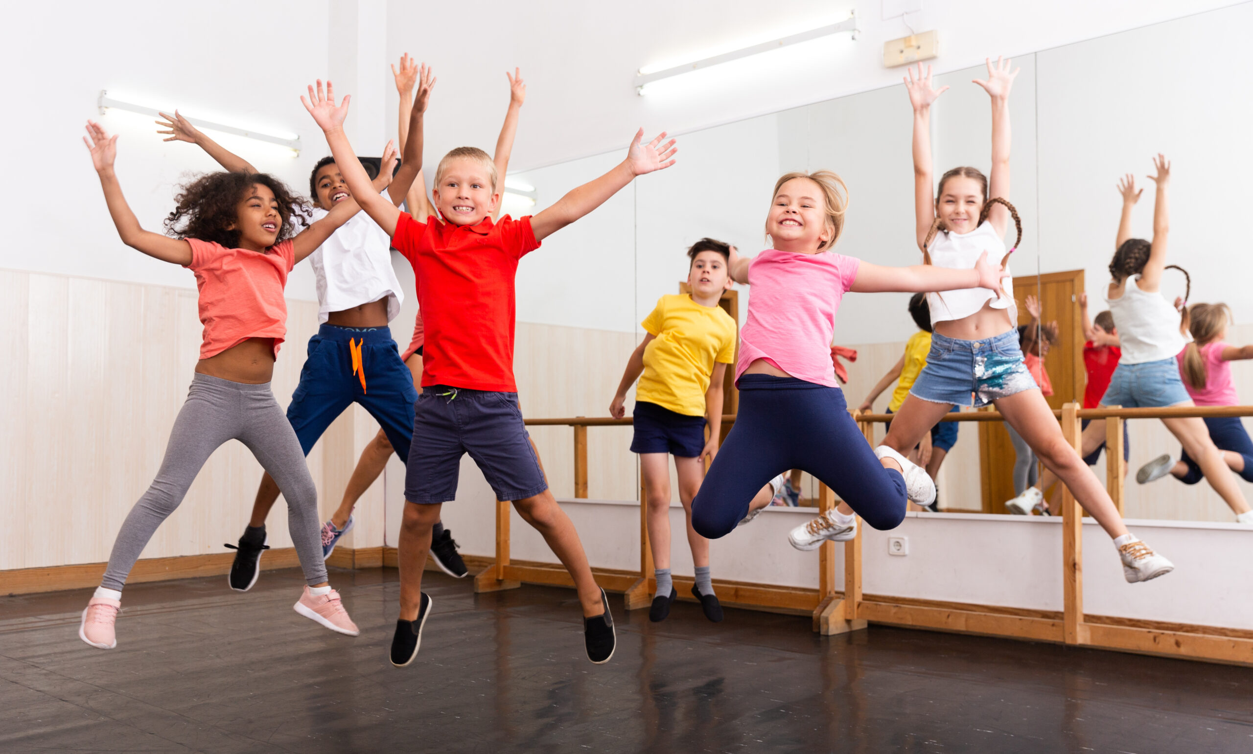 Happy kids of different nationalities and ages jumping during class in dance school